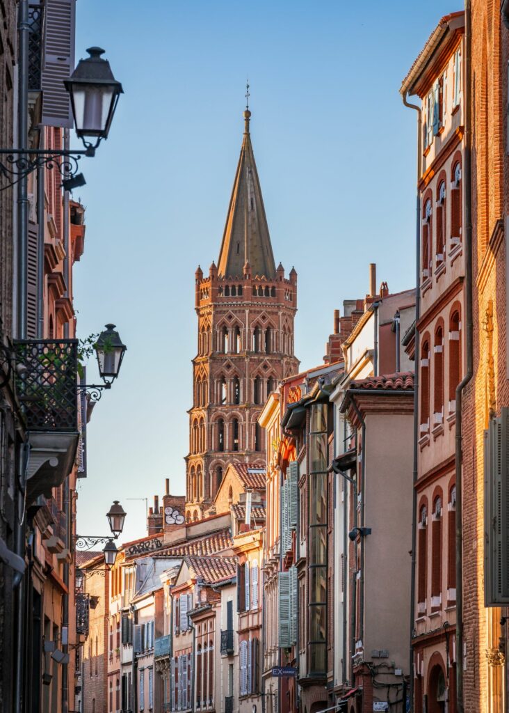 Rue typique de Toulouse avec la basilique Saint-Sernin en arrière-plan et façades en briques rouges