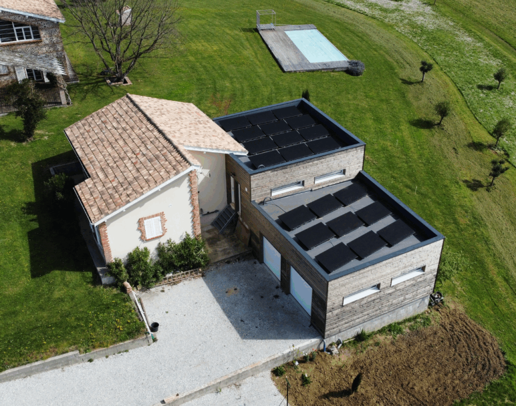 Vue aérienne d’une maison agrandie avec bardage bois et toiture plate sur terrain verdoyant.