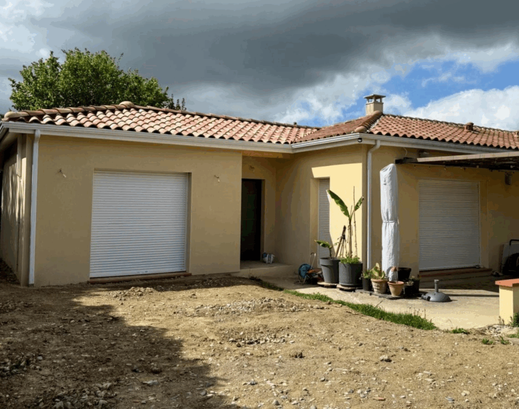 Maison de plain-pied avec toits en tuiles et volets roulants, après extension récente.