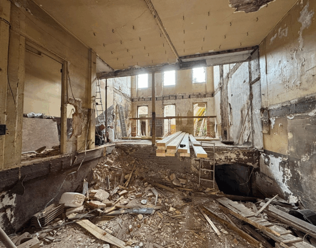 Travaux sur immeuble à Toulouse avec mini-pelle devant une façade en brique, accès chantier en milieu urbain