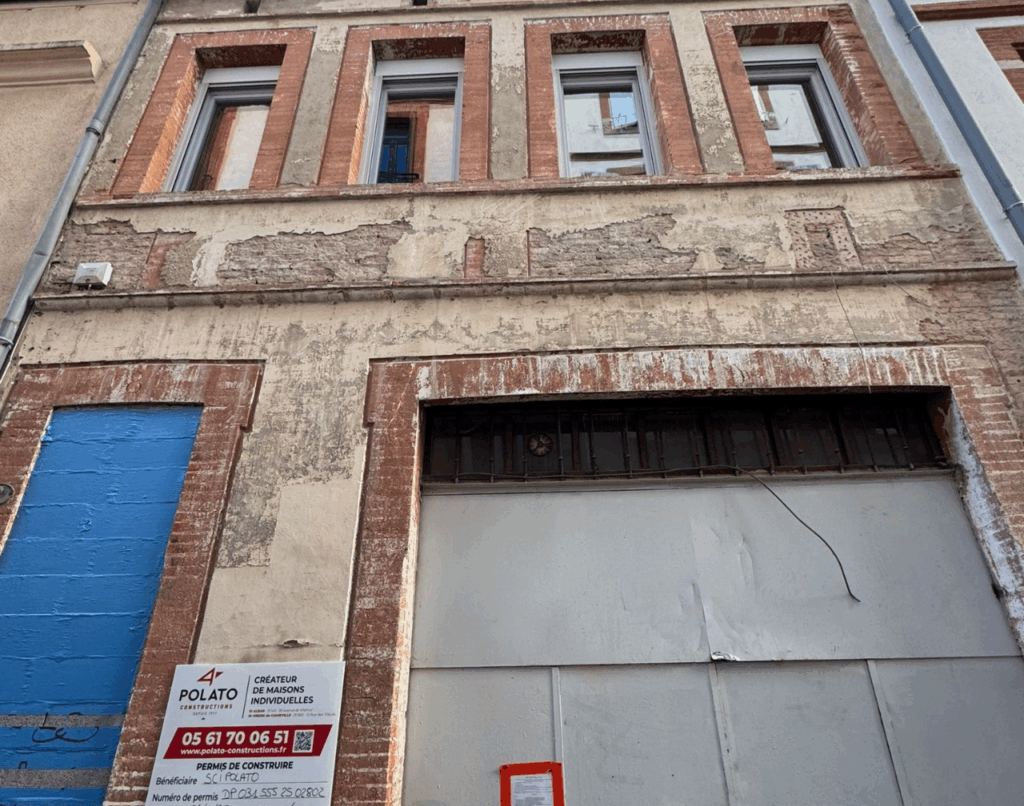 Façade d’immeuble à Toulouse en briques apparentes avec enduits partiellement déposés