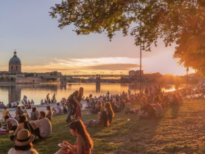 Couché de soleil sur les bords de la Garonne à Toulouse, avec une foule réunie face au Dôme de La Grave